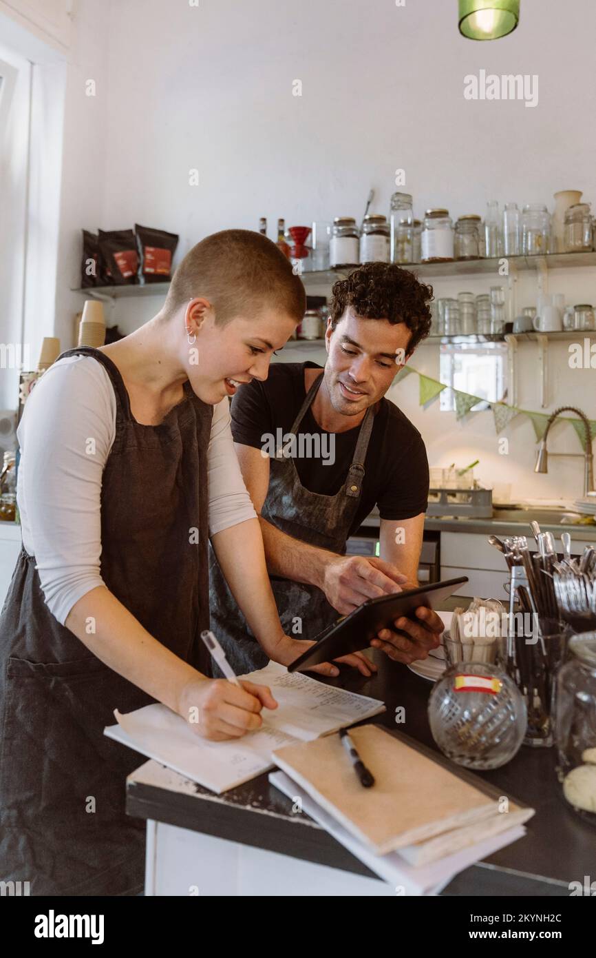 Un propriétaire de sexe masculin partage un PC tablette avec une collègue de sexe féminin au café Banque D'Images