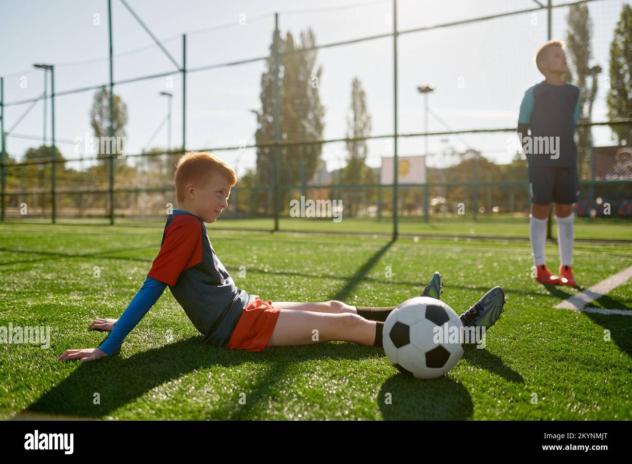 Un jeune joueur de football de garçon reste sur le terrain pendant la pause dans l'entraînement Banque D'Images