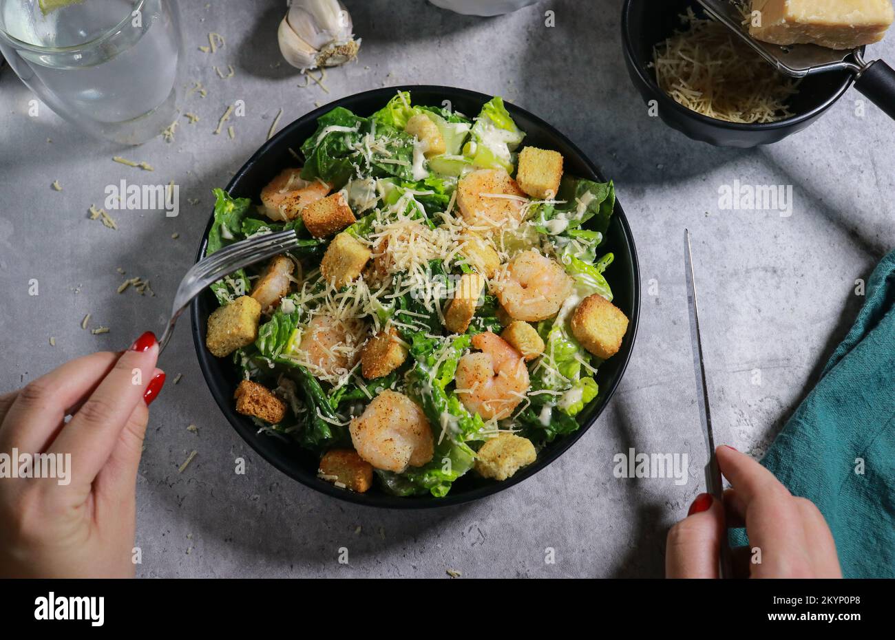 Gros plan de la femme mangeant de la salade César à la fourchette sur une table en marbre gris Banque D'Images