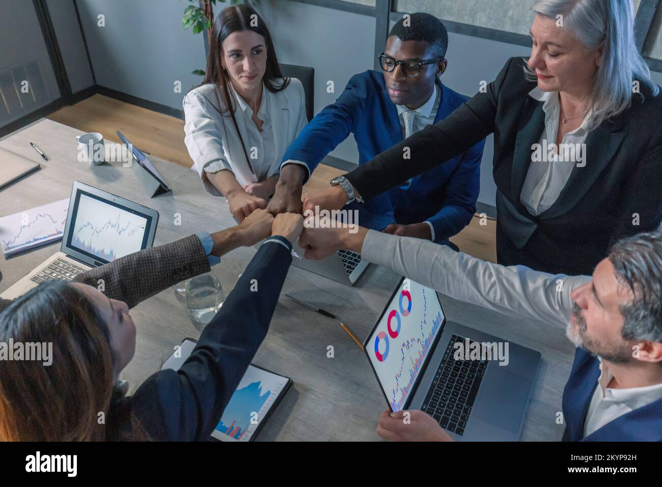 Des gens d'affaires multiraciaux motivés et heureux, jeunes et plus âgés, se joignent aux poings, font preuve de soutien et d'esprit d'équipe ensemble, célébrant l'entreprise Banque D'Images