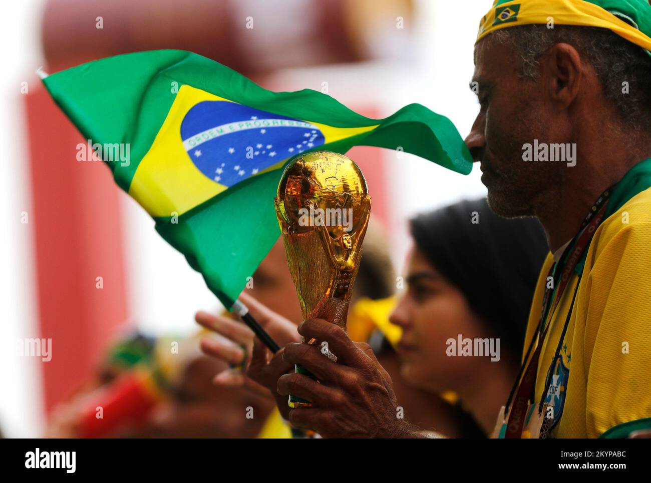 Réplique du trophée de la coupe du monde de la FIFA en gros plan et drapeau brésilien. Un fan de football tient un prix pour fêter son événement et soutient l'équipe nationale de football Banque D'Images