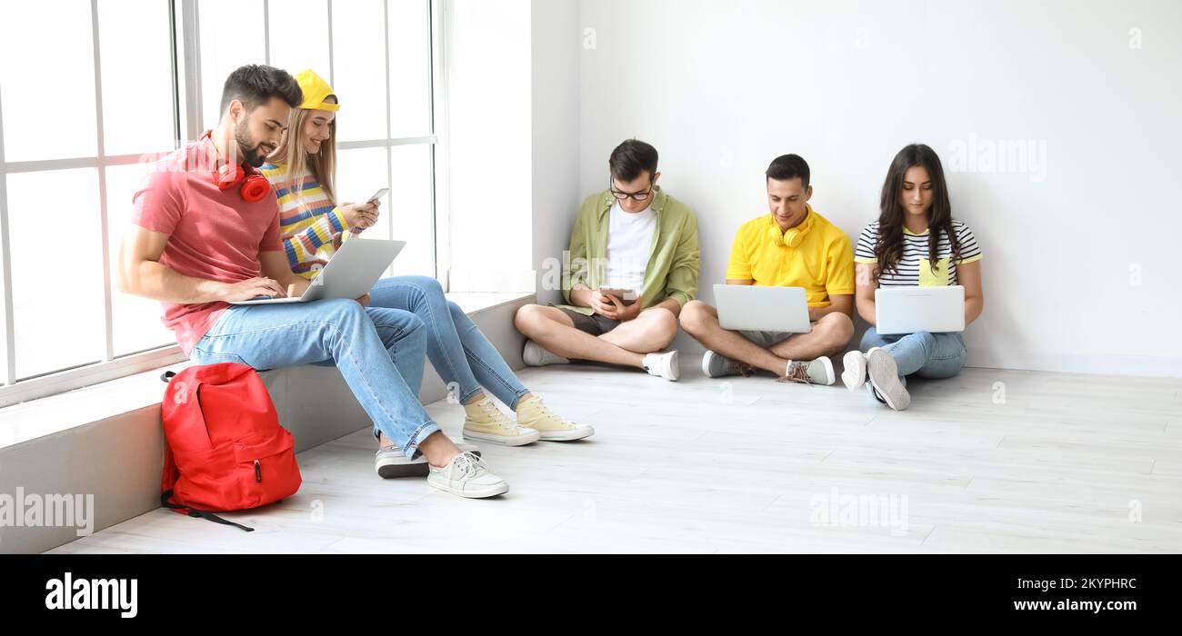 Étudiants avec des appareils modernes dans le couloir Banque D'Images