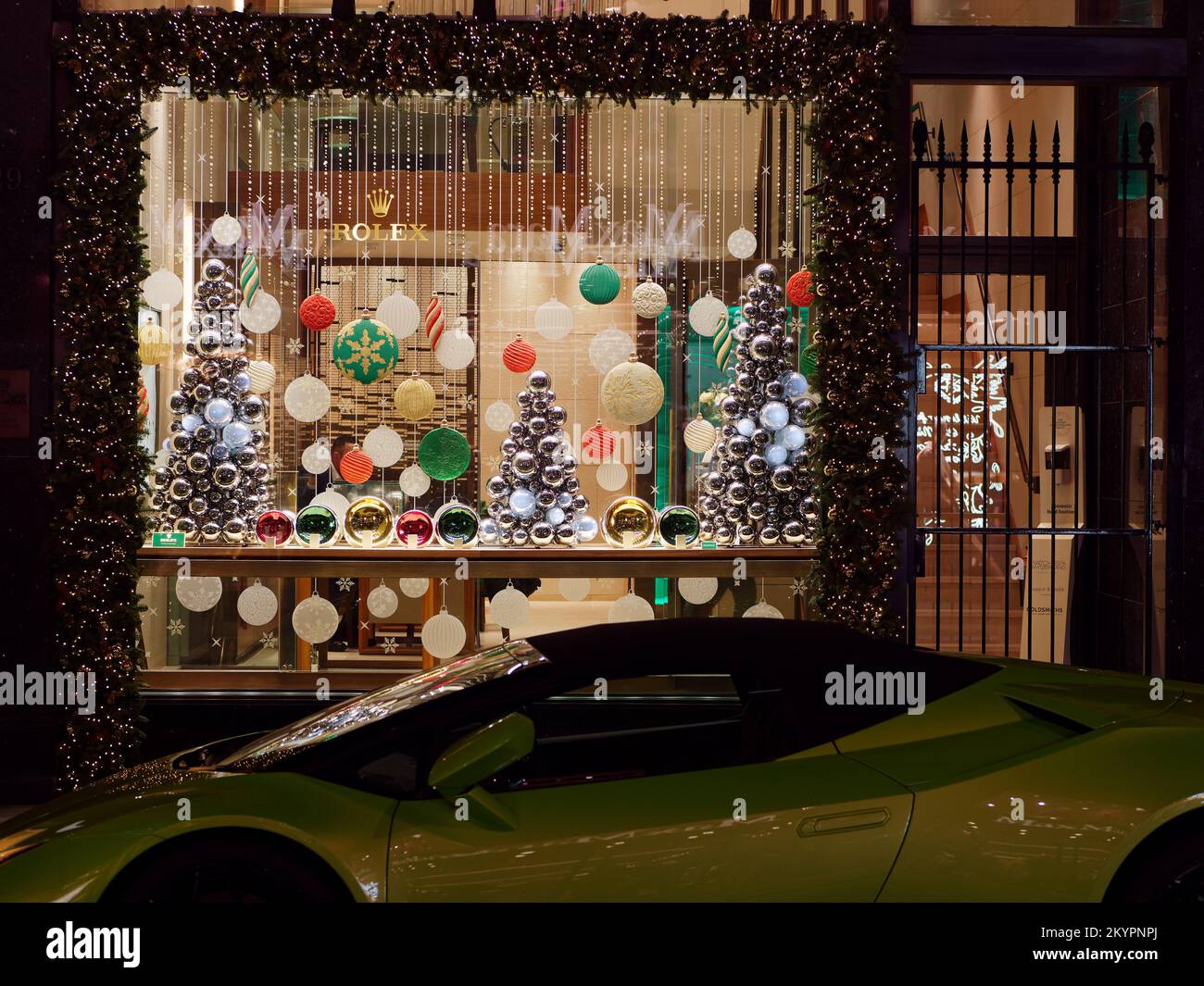 Stockez sur Old Bond Street avec un présentoir de Noël comprenant des formes de sapin de Noël, avec une voiture de sport garée en face, Londres. Banque D'Images