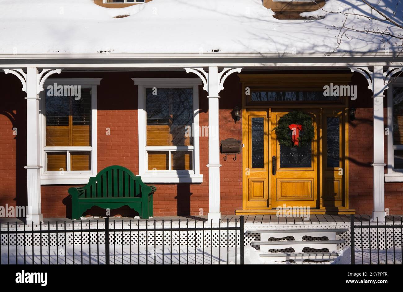 Ancienne maison de style Canadiana en briques rouges de 1870 avec couronne de Noël sur la porte d'entrée en hiver. Banque D'Images
