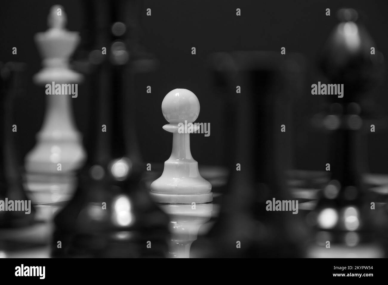La protection à tout prix : cette image en noir et blanc présente un seul Pawn avec le défi de protéger son Roi. Banque D'Images