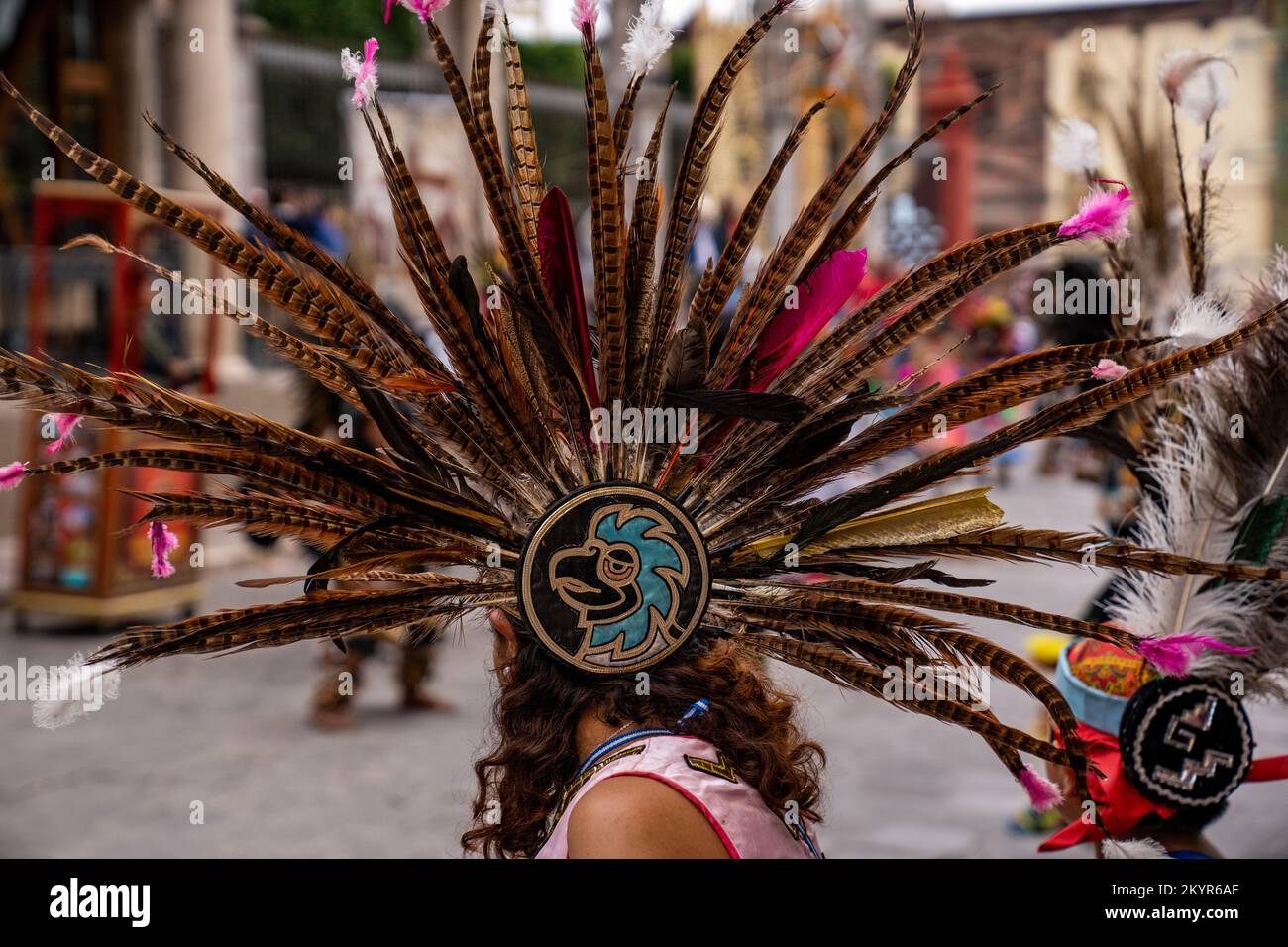 Femme portant une robe à tête de plumes faisante avec un emblème d'aigle au rassemblement de tribus indigènes de Danza de Indios à San Miguel de Allende, Mexique Banque D'Images