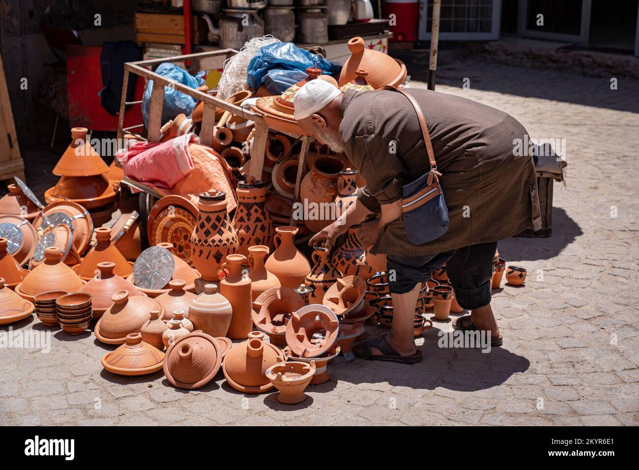 Homme à barbe blanche parcourant des pots d'argile et des tagines au Souk, dans la médina de Marrakech, au Maroc Banque D'Images