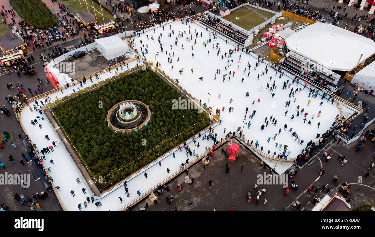 De nombreuses personnes patinent sur la patinoire blanche à l'extérieur le jour d'hiver. Vue aérienne de drone. Nouvel an fête de Noël vacances fond. Paysage urbain panoramique. Style de vie récréation activité Banque D'Images