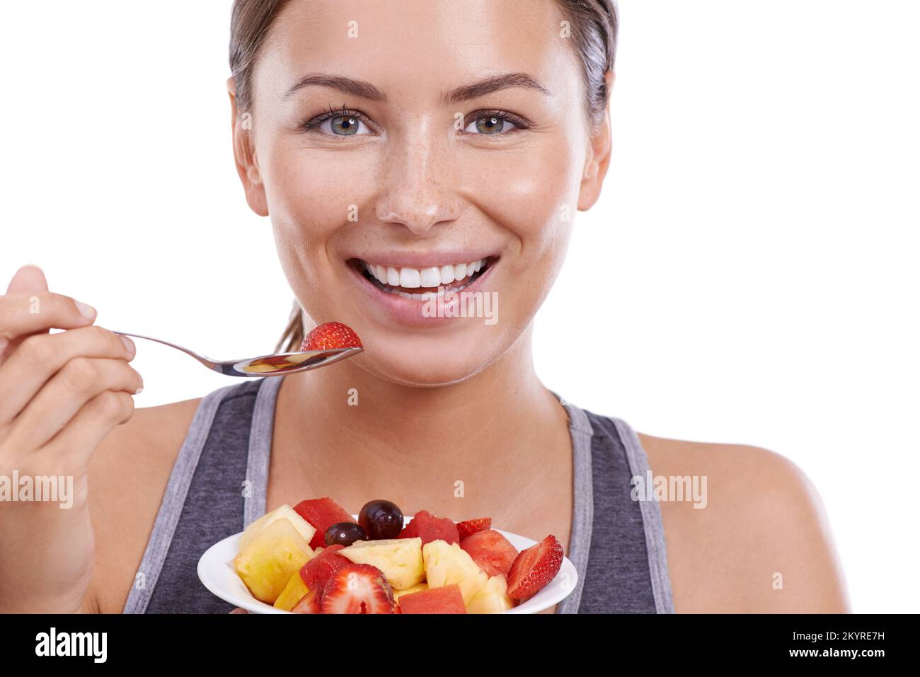 Elle aime vivre de façon saine. Portrait d'une jeune femme attrayante mangeant un bol de salade de fruits. Banque D'Images