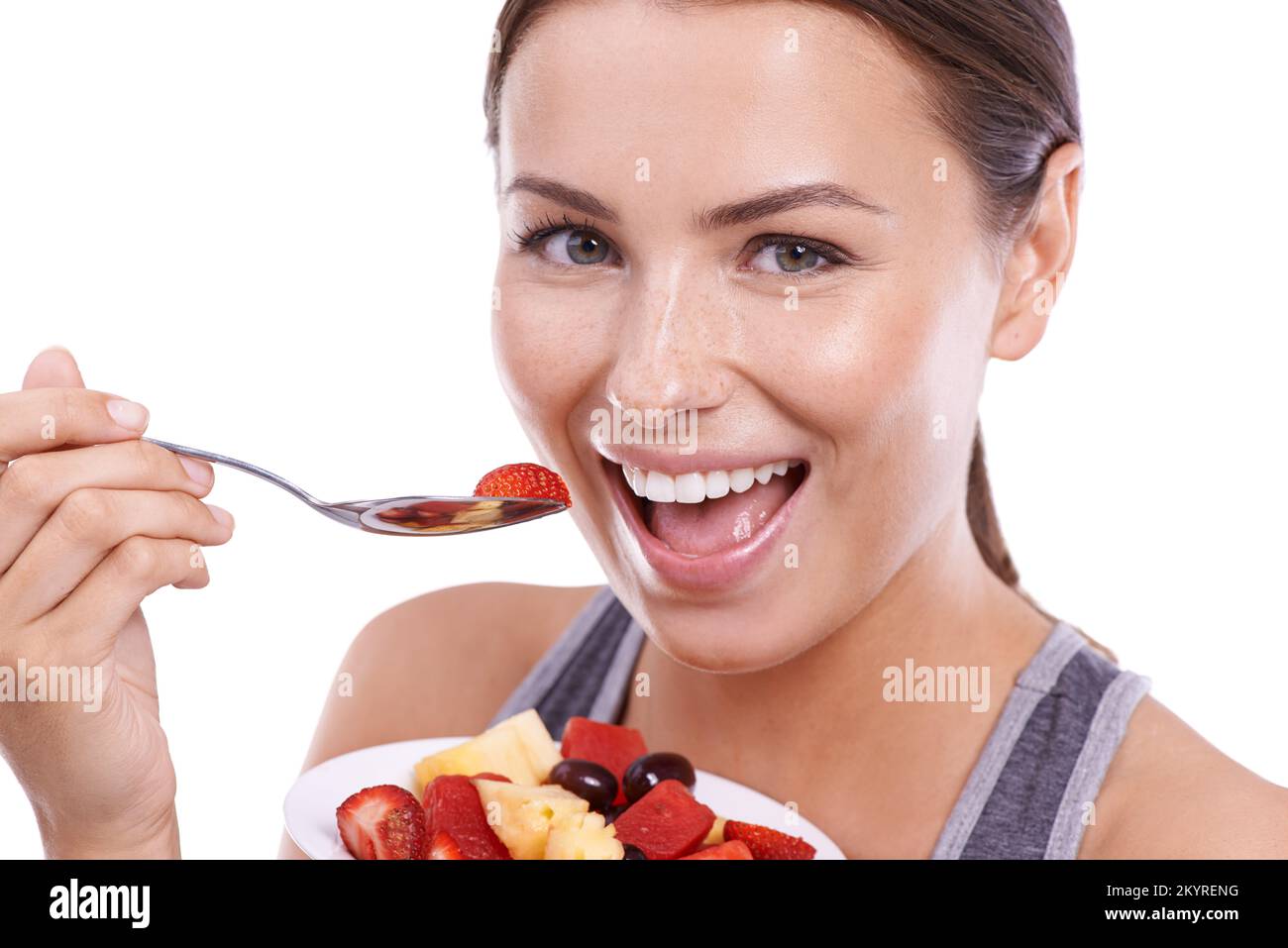 Elle aime vivre de façon saine. Portrait d'une jeune femme attrayante mangeant un bol de salade de fruits. Banque D'Images