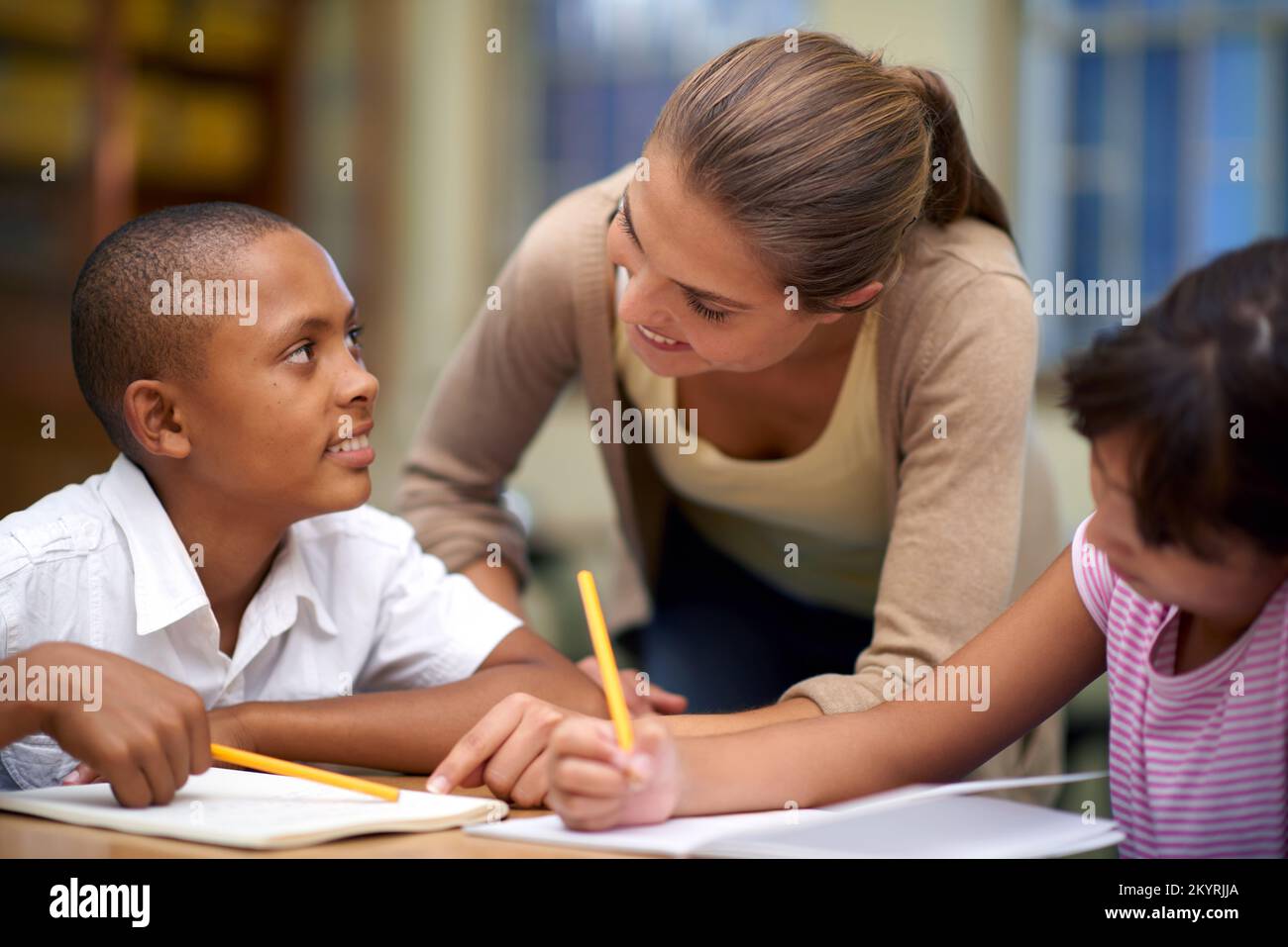 Elle enseigne de son cœur. une enseignante aidant ses élèves avec leur travail dans la salle de classe. Banque D'Images