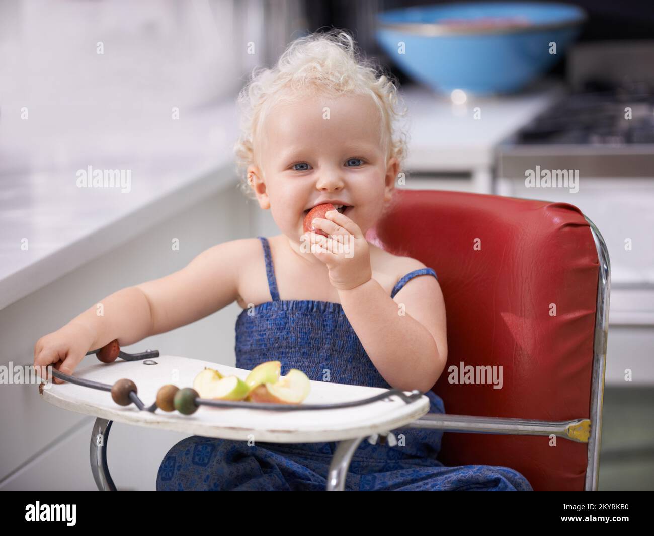 Piquer dans cette pomme. Une petite fille mignonne avec des cheveux bouclés piquant dans une pomme. Banque D'Images