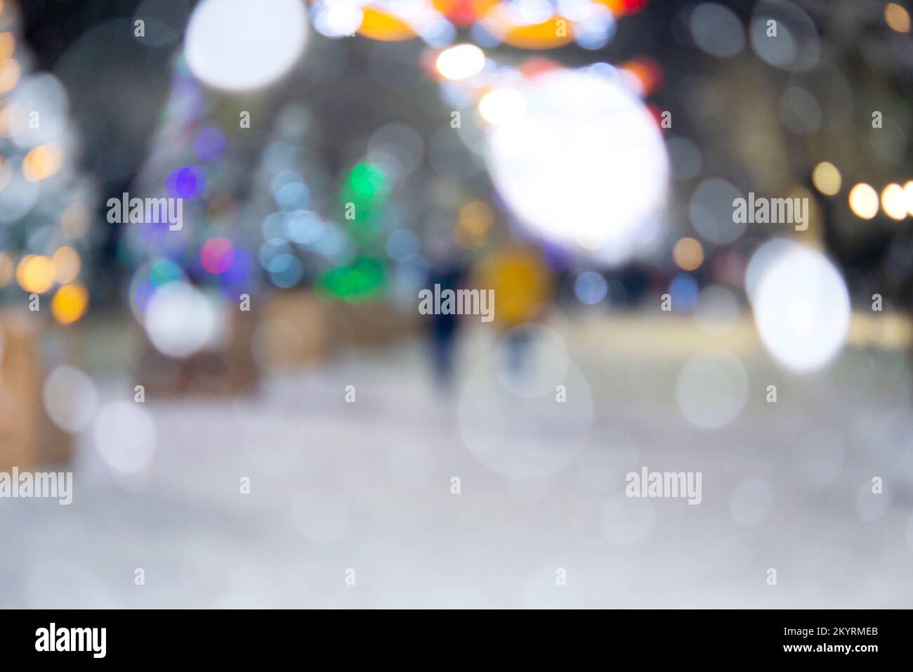 Arrière-plan flou. Rue de la ville pendant les chutes de neige en hiver. Beaucoup d'arbres de Noël décorés, éclairage, décoration sur la rue. Fête de Noël du nouvel an. Lanternes sur les arbres Banque D'Images
