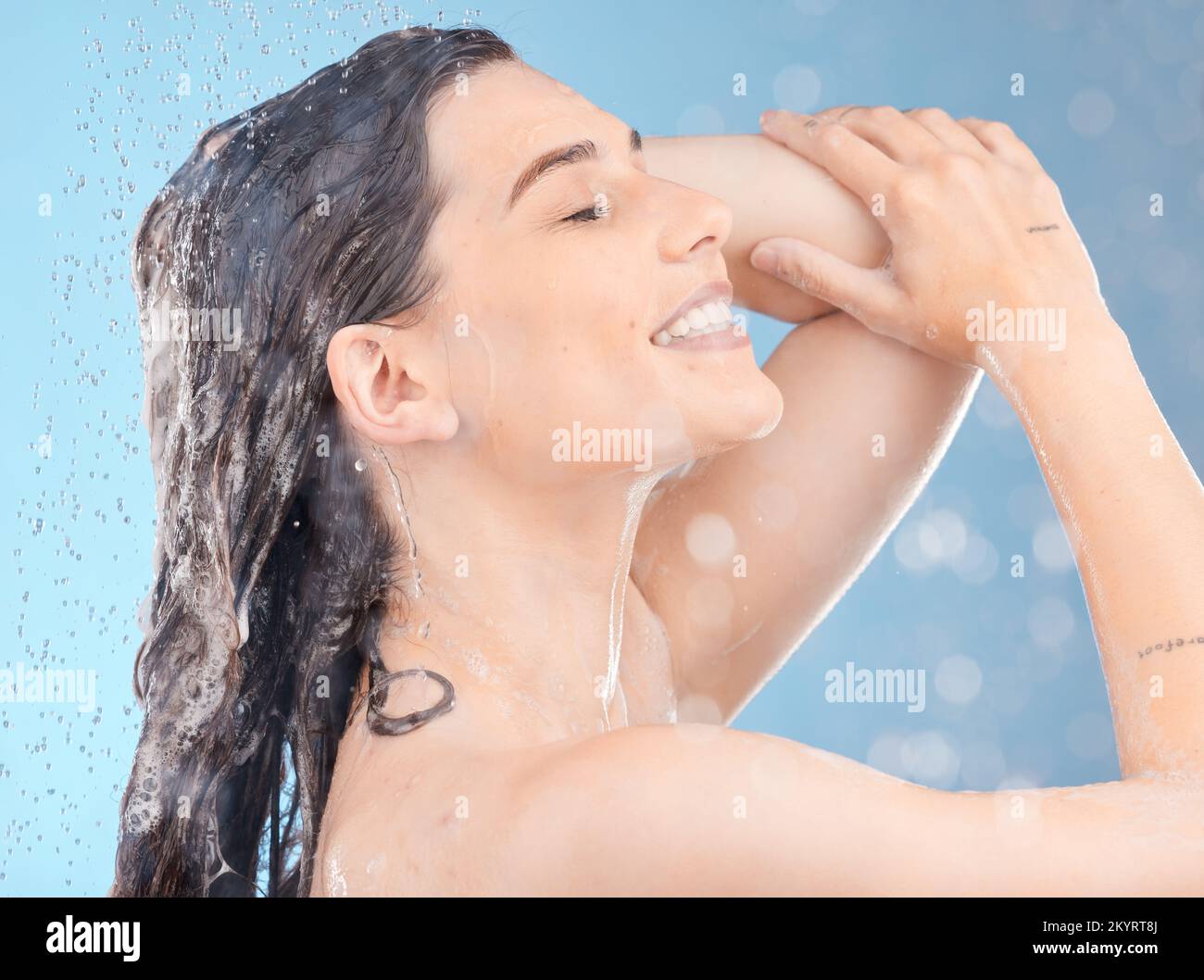 Douche, nettoyage et femme avec de l'eau pour les cheveux en studio pour les soins de la peau, les soins du corps et le bien-être sur fond bleu. Soins de soi, hydratation et fille Banque D'Images