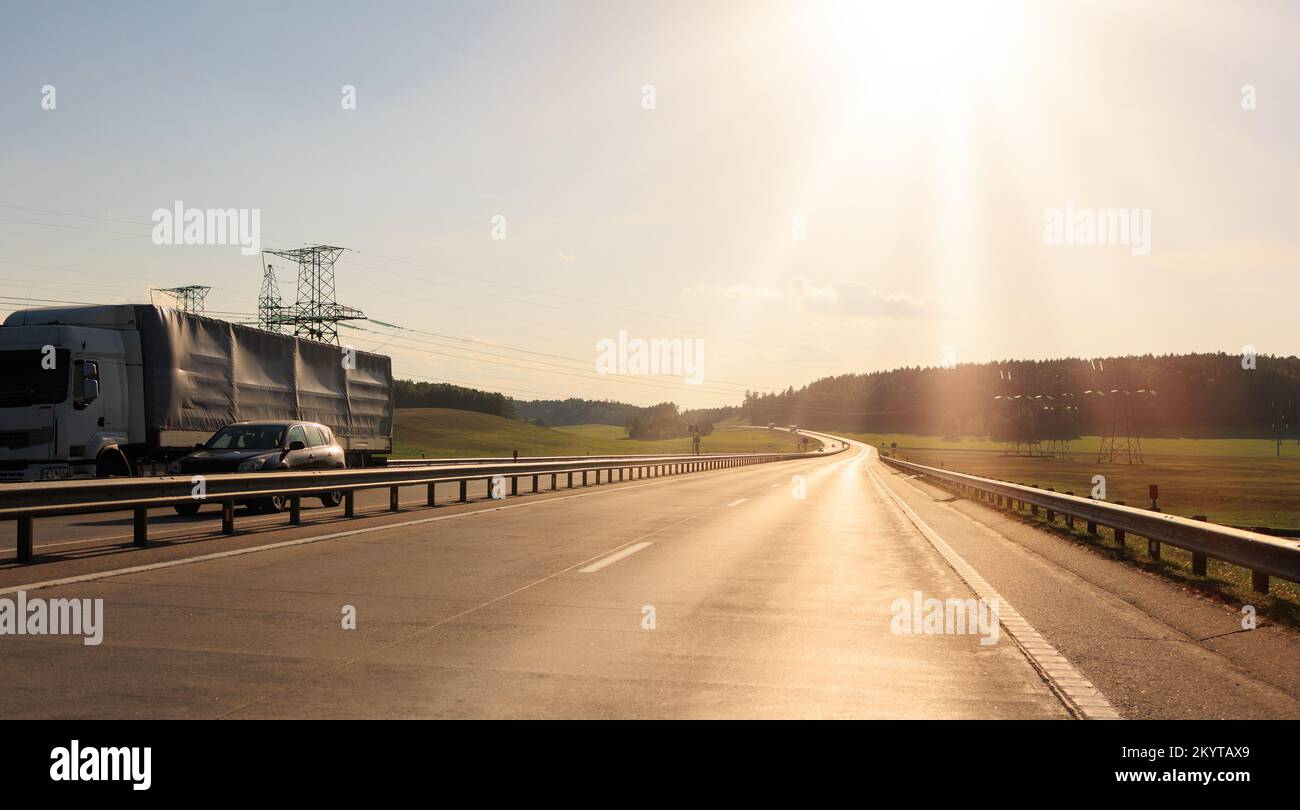 Route large, transport et ciel bleu avec nuages par jour d'été Banque D'Images