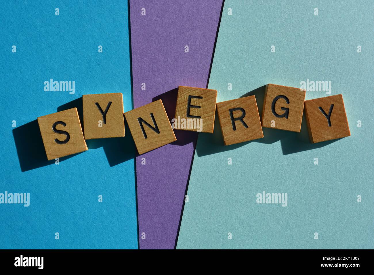 Synergy, mot à la mode d'affaires en lettres de l'alphabet en bois isolées sur fond bleu et violet Banque D'Images