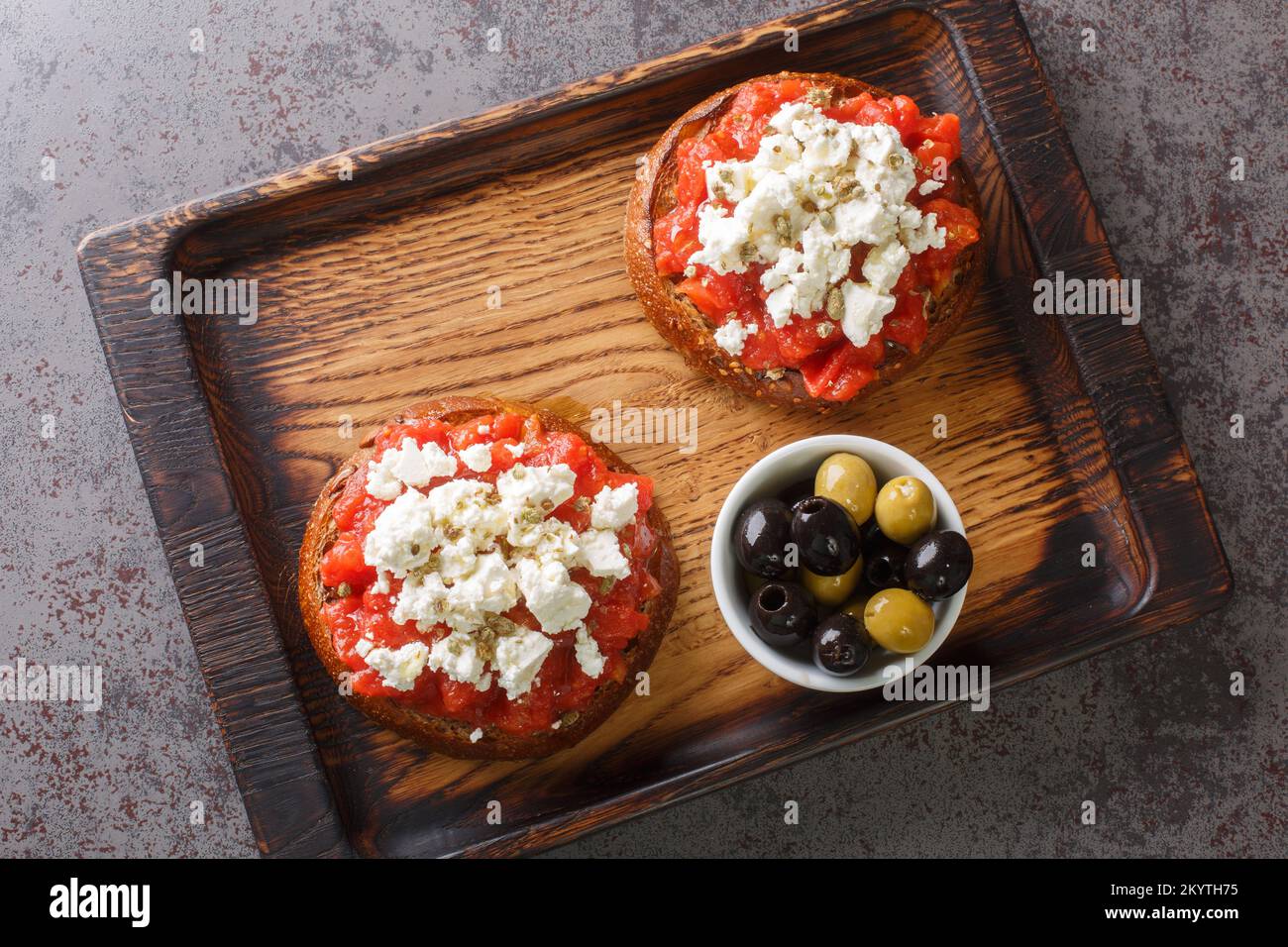Dakos se compose d'une tranche de pain d'orge craqué et garni de tomates mûres écrasées ou râpées et de feta émietté avec origan et olives closeup o Banque D'Images