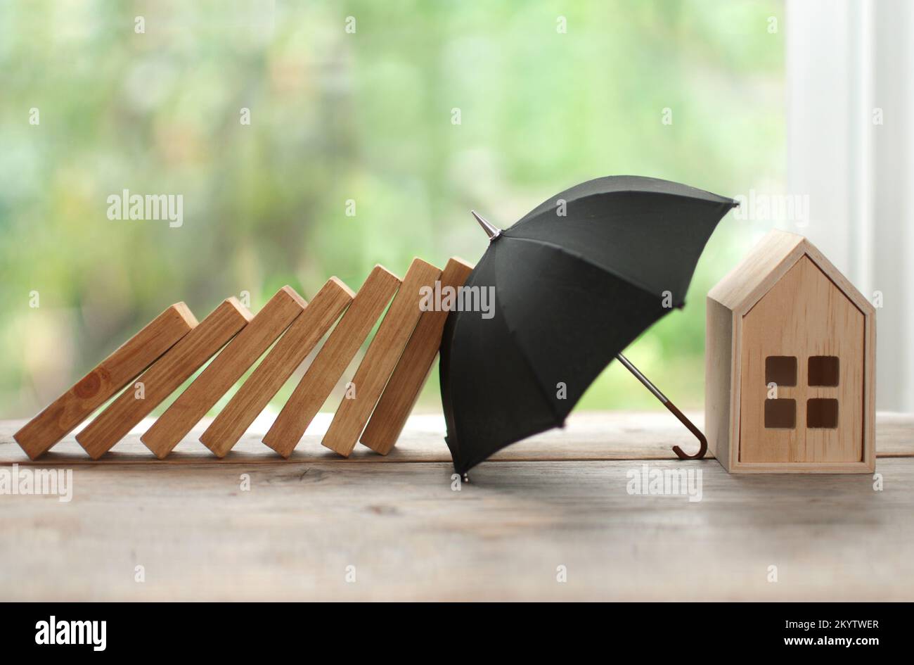 Parapluie protégeant la maison contre l'effondrement de domino, concept d'assurance Banque D'Images