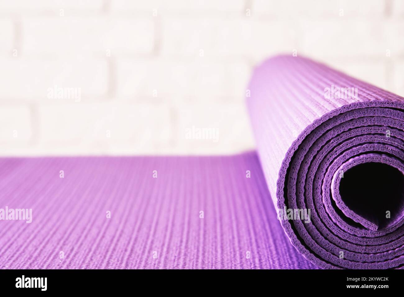 Tapis d'exercice violet près du mur de briques dans la salle de fitness. Milieux sportifs et de loisirs Banque D'Images