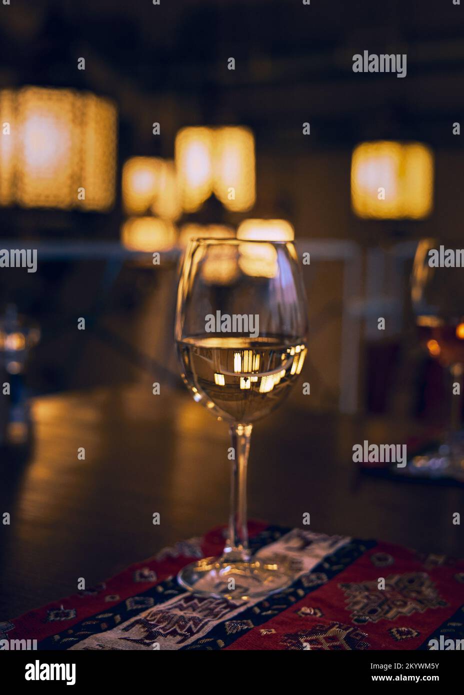 Reflet des rayons lumineux du restaurant et de l’espace environnant dans un verre de vin blanc sur une table de restaurant Banque D'Images