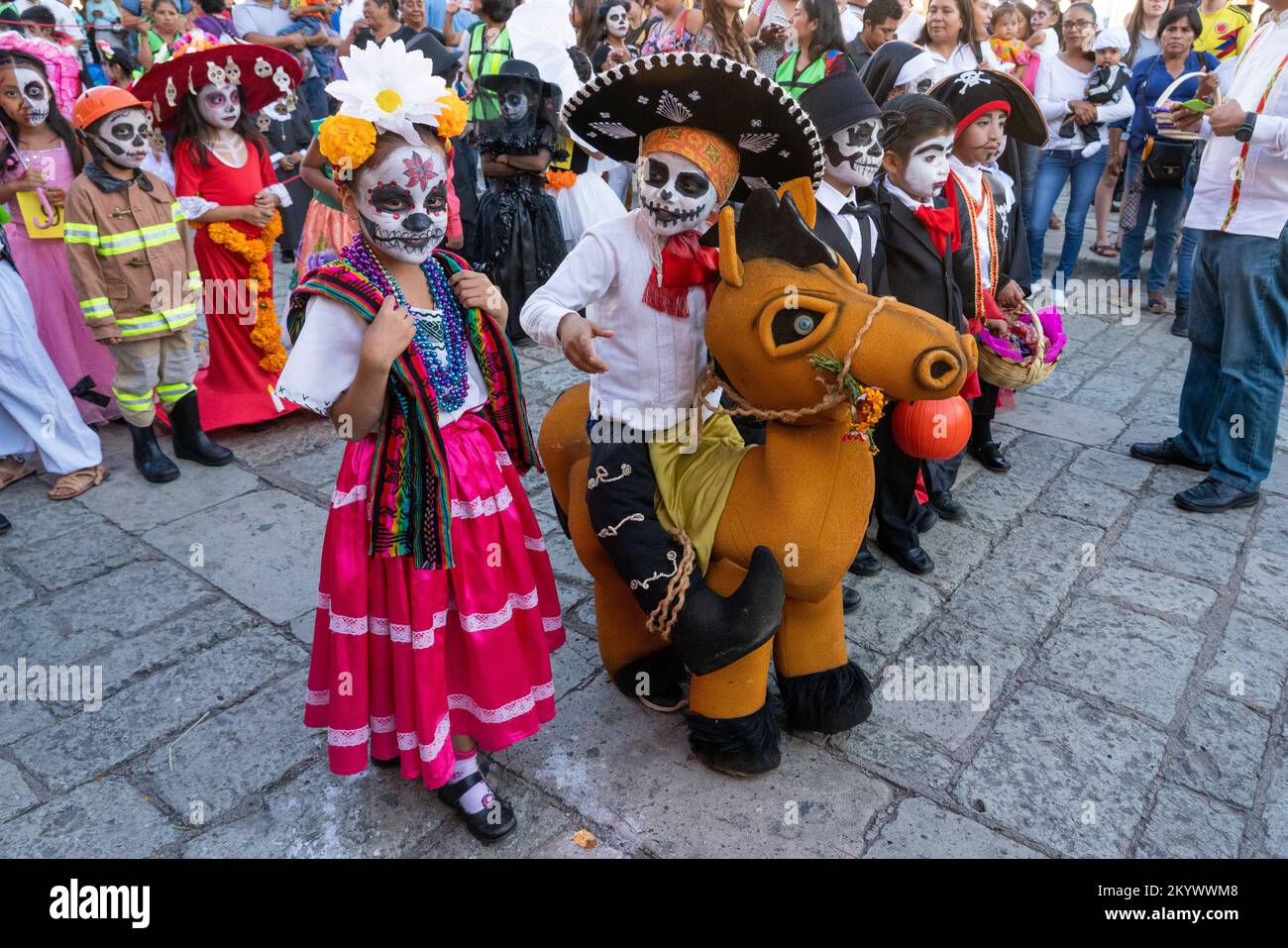 Les enfants déguisés et peints pour le visage s'alignent pour un défilé des enfants du jour des morts dans une rue à Oaxaca, au Mexique. Banque D'Images