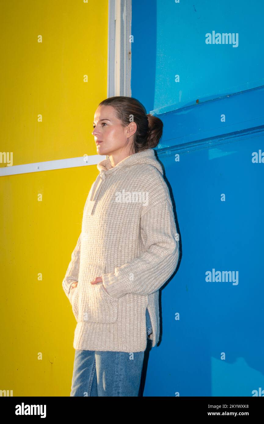 Adulte moyen femme attrayante debout contre un mur bleu et jaune. Banque D'Images