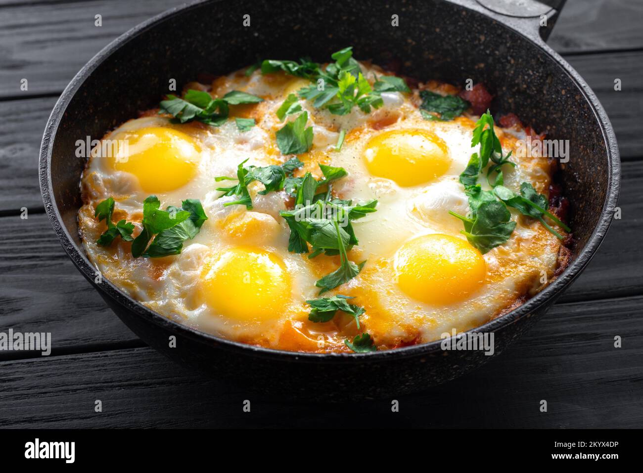 Œufs Shakshuka dans une poêle sur fond de bois noir. Œufs pochés dans une sauce épicée aux tomates et au poivre. Œufs brouillés juifs traditionnels. Haut Banque D'Images