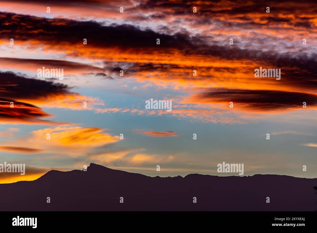 Des nuages lenticulaires spectaculaires à l'aube au-dessus de la silhouette des sommets de la Sierra Nevada (Grenade, Espagne) en automne Banque D'Images