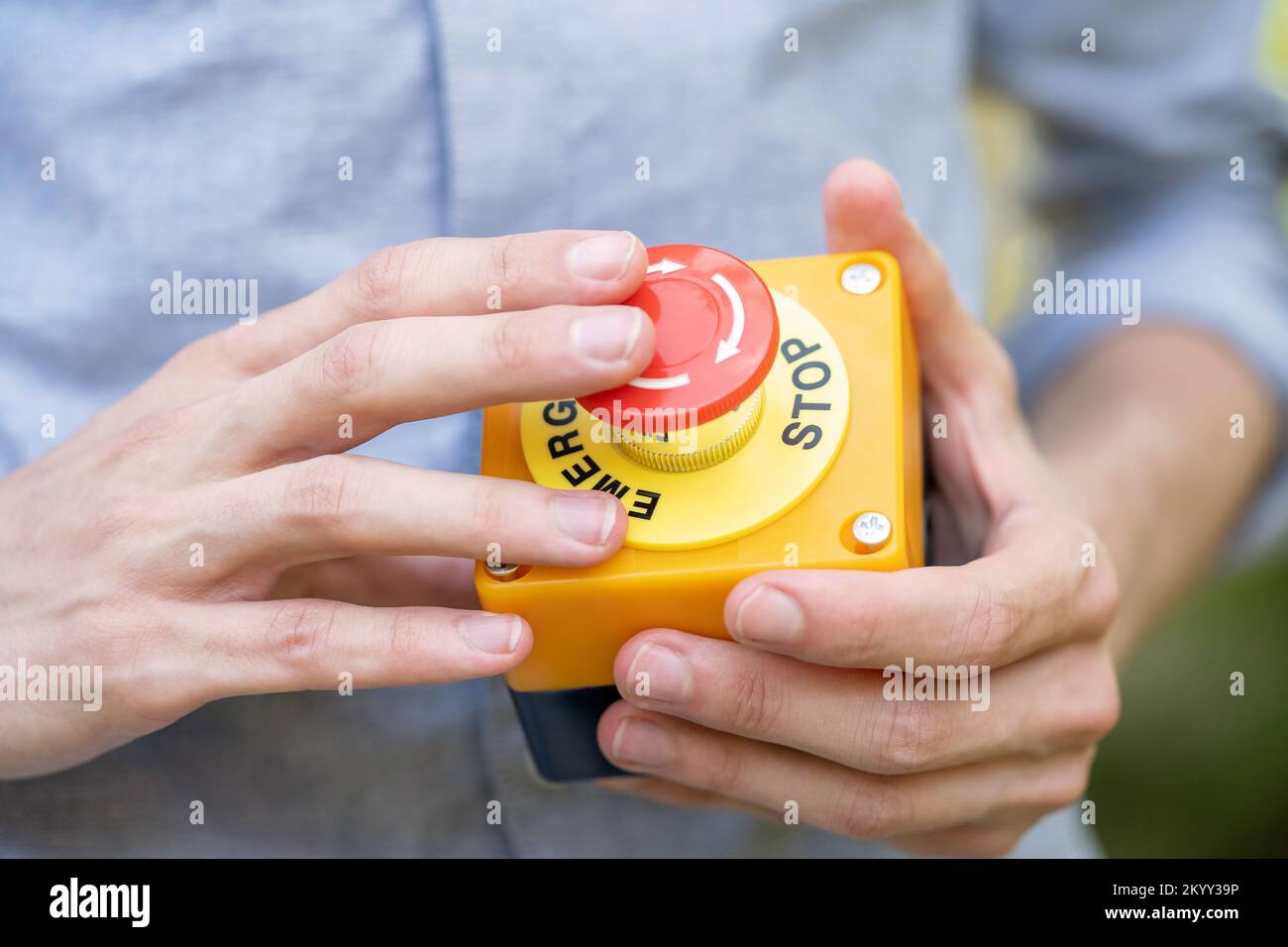 Homme anonyme appuyant sur un bouton d'arrêt d'urgence de la machine de sécurité industrielle, détails de l'objet, clôture règles de sécurité du lieu de travail, politiques, sécurité Banque D'Images
