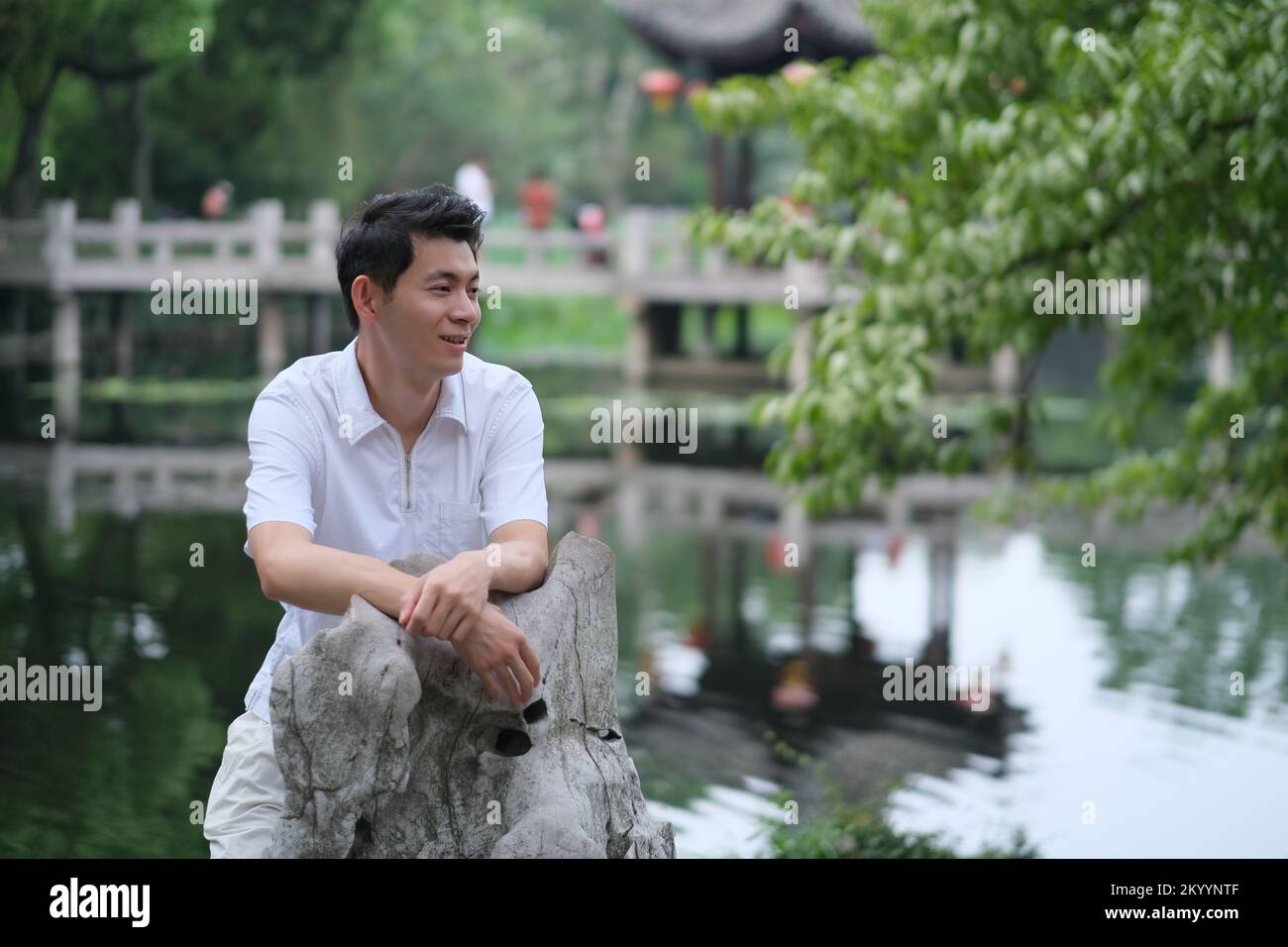 Jeune homme chinois souriant au parc extérieur, vue latérale Banque D'Images