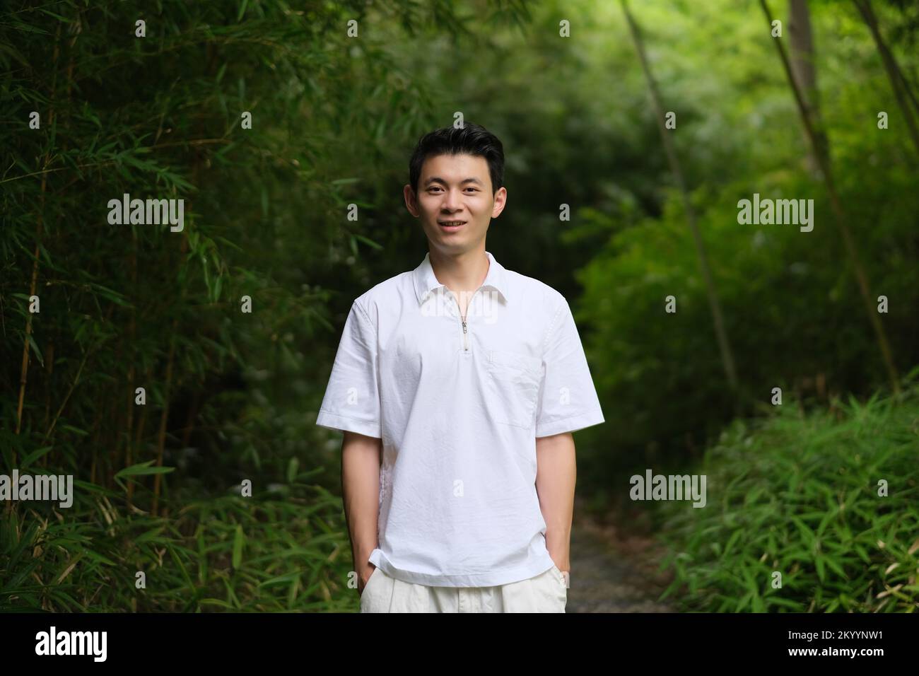 Jeune homme asiatique à la forêt verte de bambou, souriant à la caméra Banque D'Images