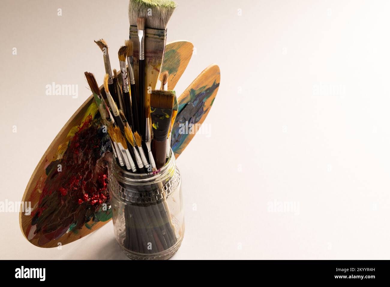 Composition du pot de pinceaux et de la palette sur fond blanc Banque D'Images