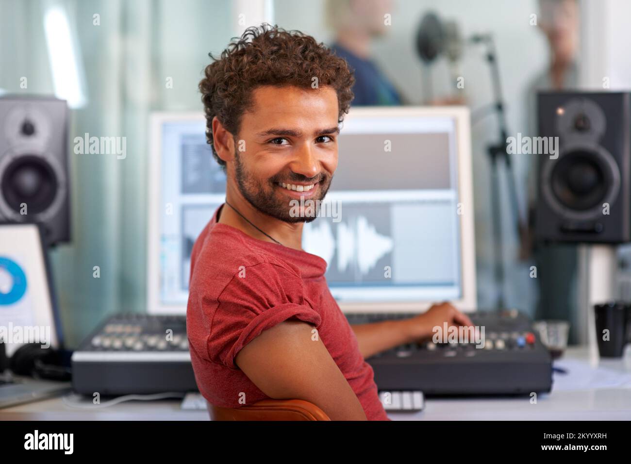Créons un surmontoir de graphique. Un beau jeune ingénieur du son assis devant son bureau de mixage - portrait. Banque D'Images