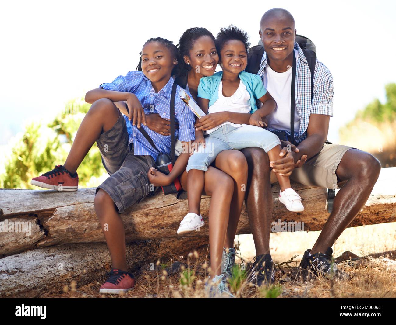 Ils adorent faire une bonne randonnée ensemble. Portrait d'une famille heureuse assise sur une bûche pendant une randonnée ensemble. Banque D'Images
