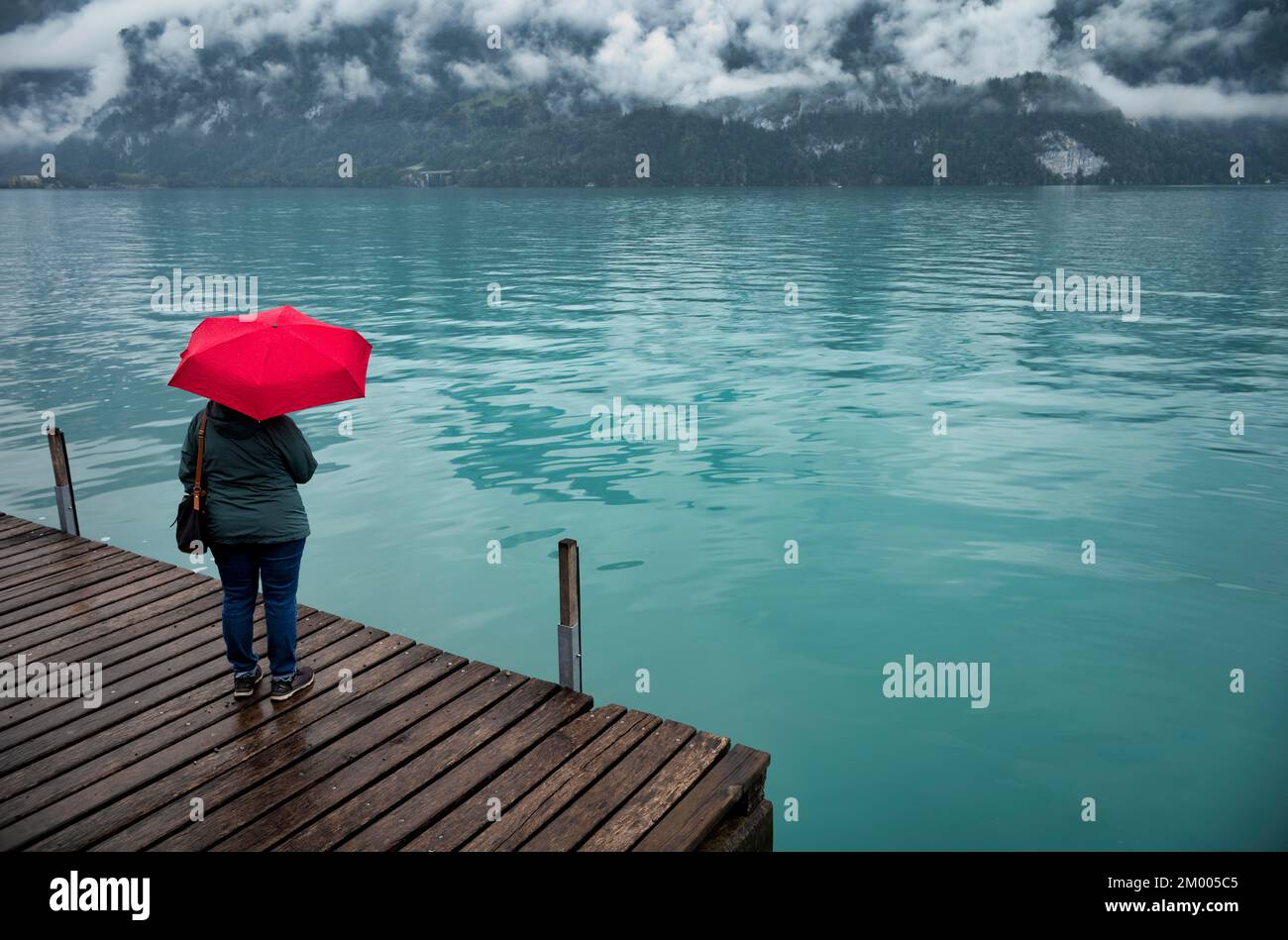 Femme plus âgée, meilleure-pageur, avec parapluie rouge, mauvais temps, promenade au bord du lac de Brienz, Brienz, canton de Berne, Oberland bernois, Suisse, Europe Banque D'Images