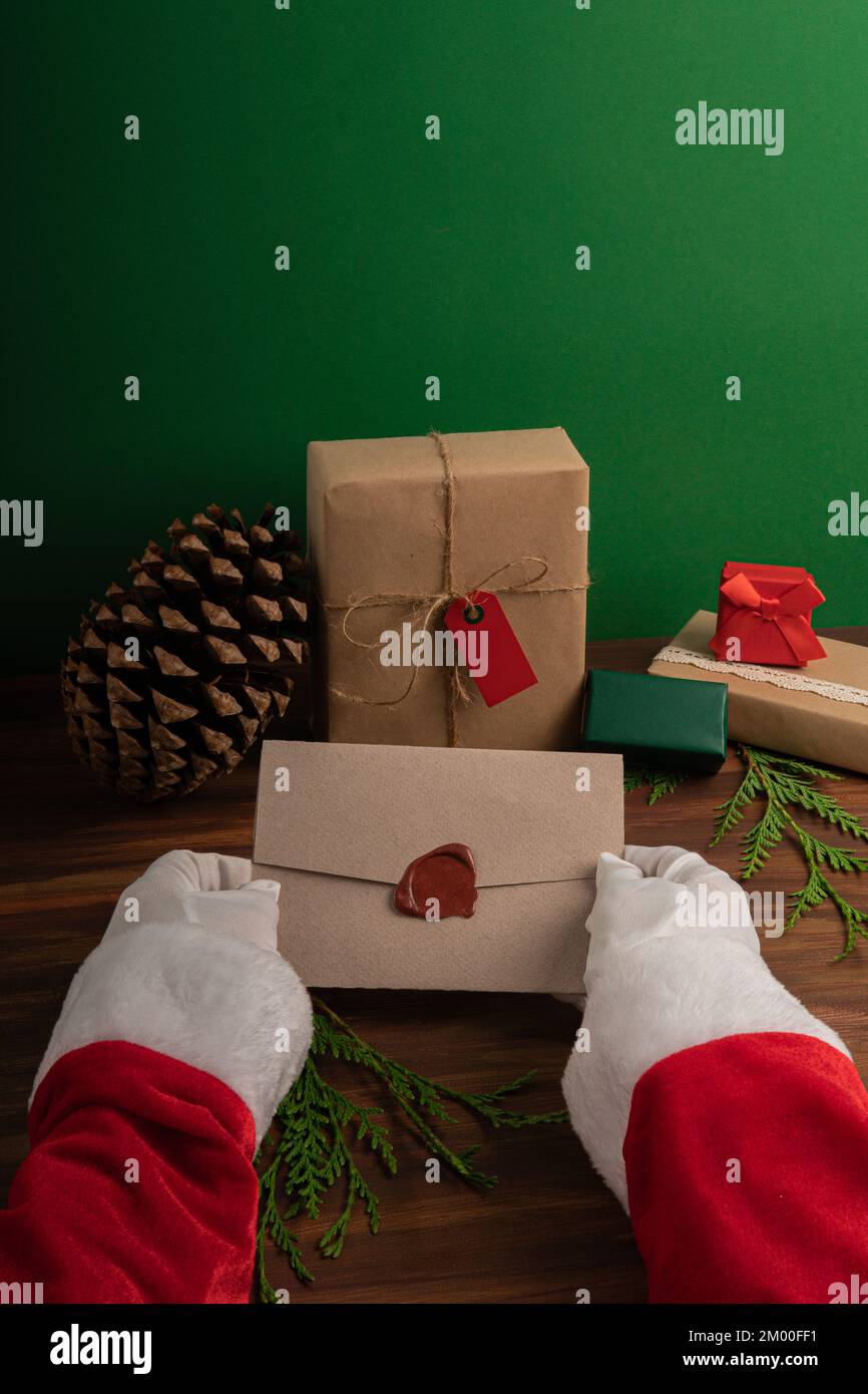 Le Père Noël lit les souhaits des enfants la veille de Noël sur fond de bois et de vert Banque D'Images