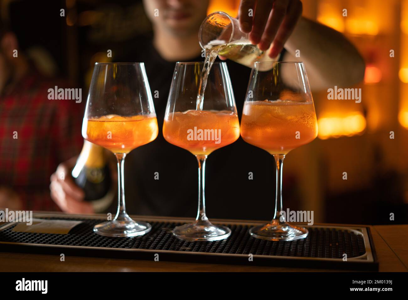 Fermez trois verres de cocktails au bar. Le barman verse un verre de vin mousseux avec Aperol. Copier l'espace Banque D'Images