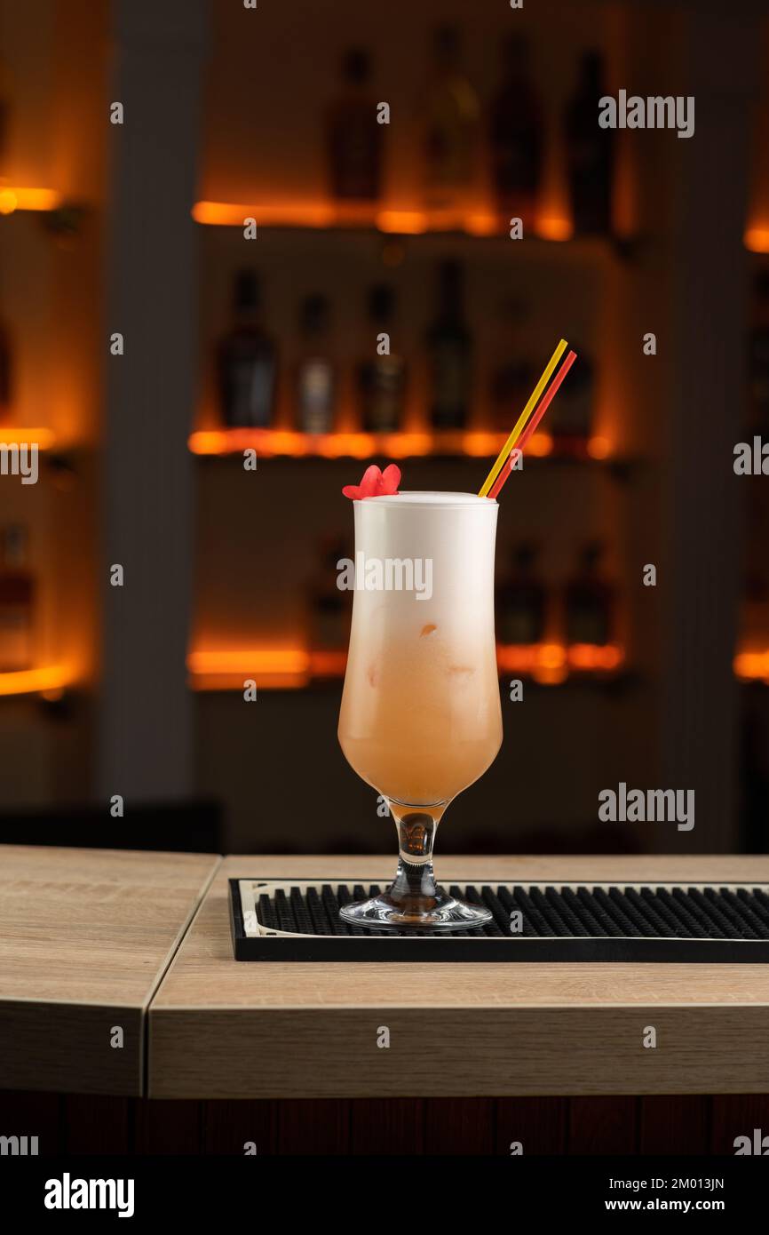 Cocktail avec liqueur de pêche et jus d'orange au bar décoré de fleurs. Copier l'espace Banque D'Images