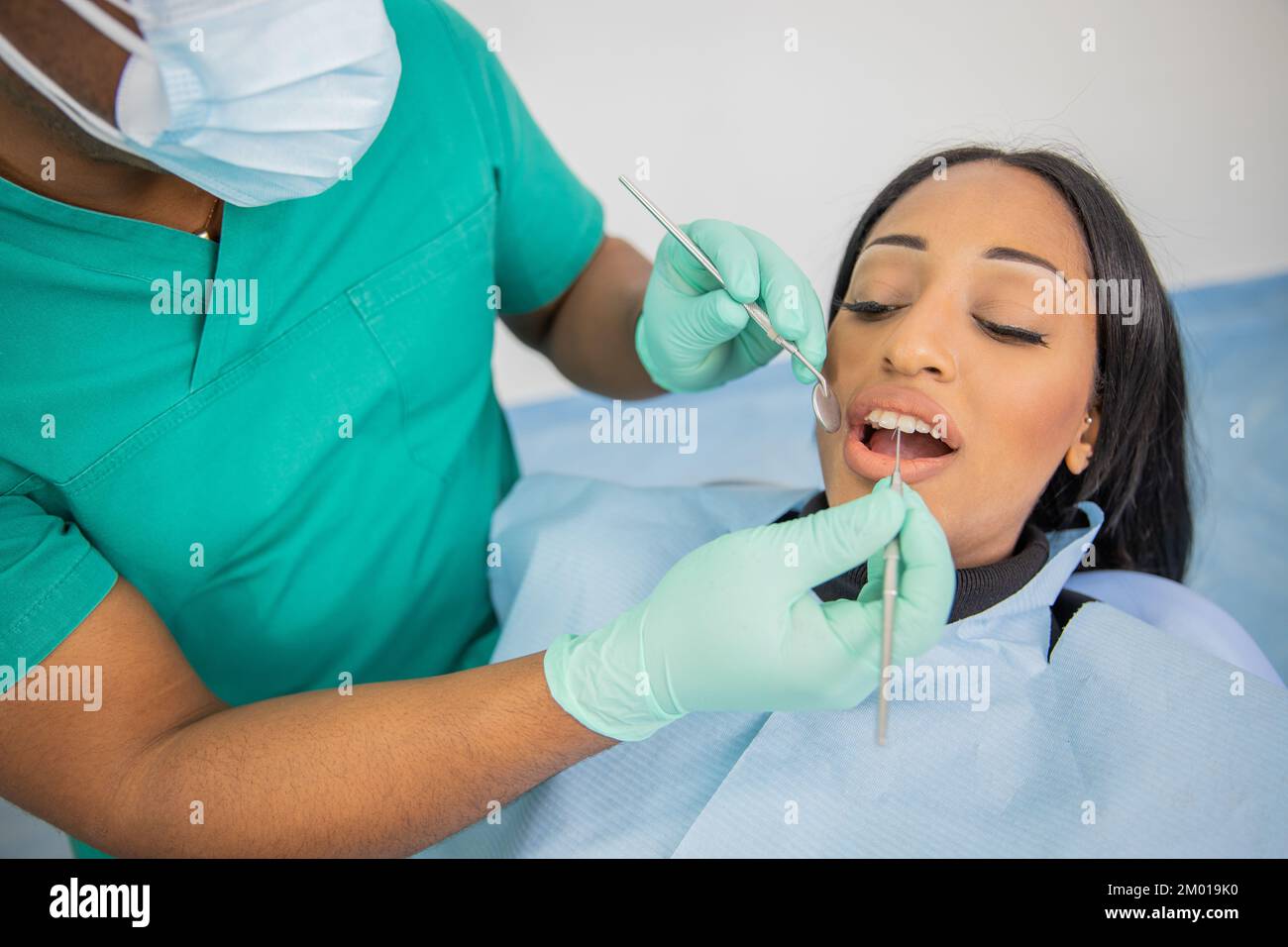 Fille au cours d'une visite dentaire, le médecin avec des outils dentaires examine sa bouche Banque D'Images