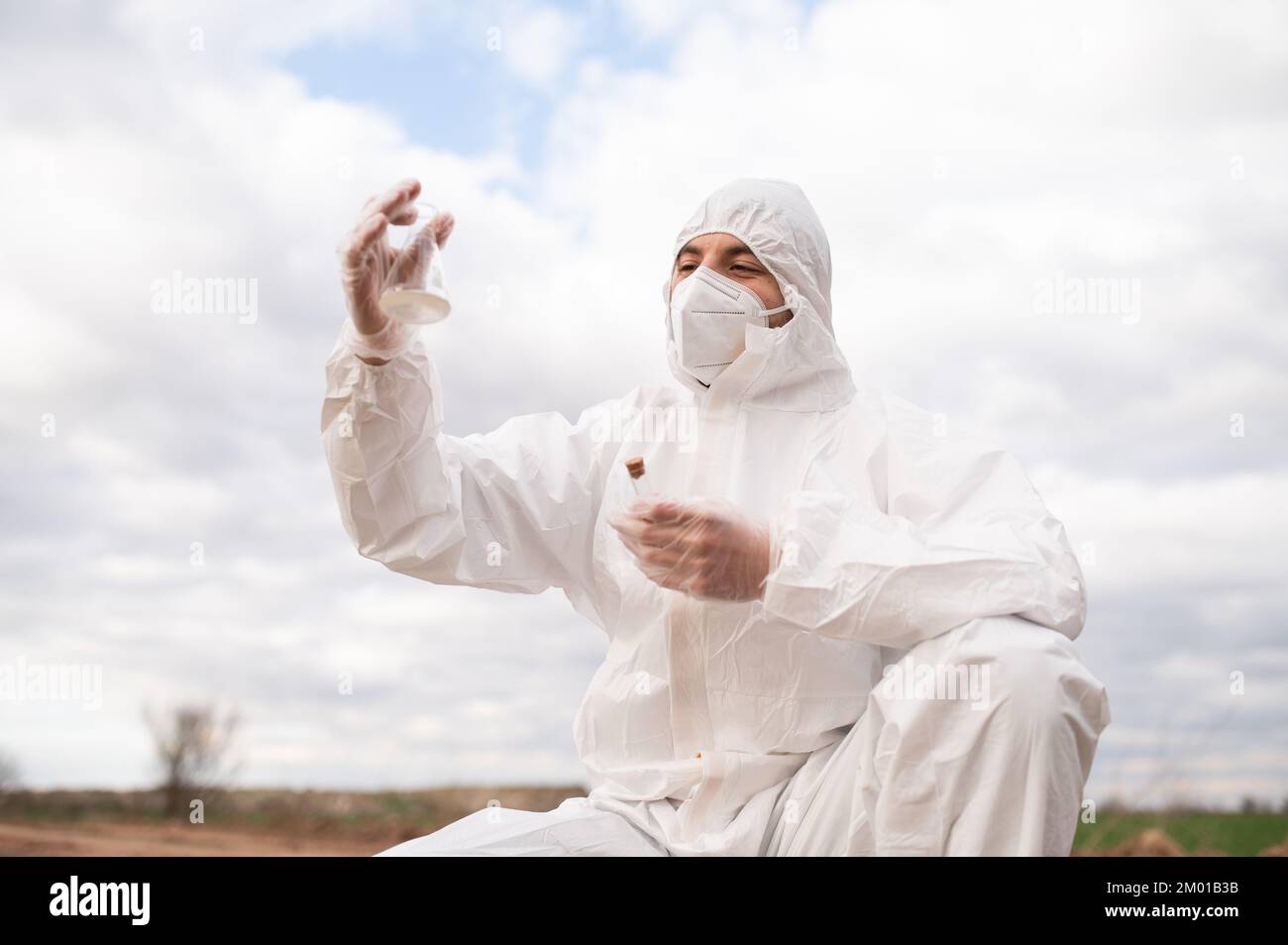 Jeune homme en costume de protection et masque travaillant comme écologiste elle examine la nature Banque D'Images