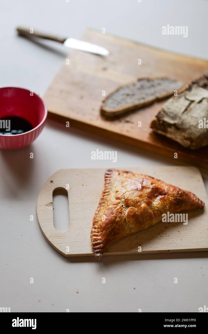 Pain de seigle maison fraîchement coupé avec pâtisserie aux pommes sur des planches à découper en bois sur une table de cuisine Banque D'Images