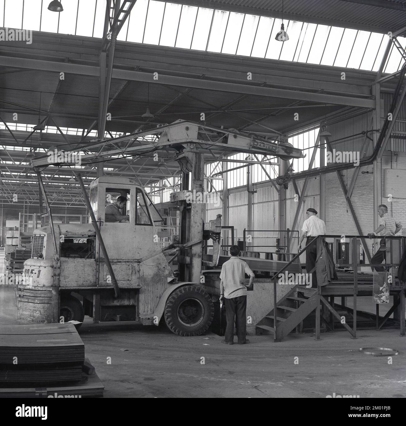 1950s, historique, steelworks, une grue de levage à rapier électrique (EME-1) de levage de la pile de tôles d'acier à l'Abbey Works, Port Talbot, pays de Galles du Sud, Royaume-Uni. La grue mobile a été fabriquée à Ipswich, dans le Suffolk, en Angleterre, par Ransomes & Rapier, l'un des principaux fabricants britanniques d'équipements et de machines ferroviaires pour travaux lourds, une entreprise qui remonte à 1869, et qui a finalement fermé plus de 100 ans plus tard en 1987. Banque D'Images