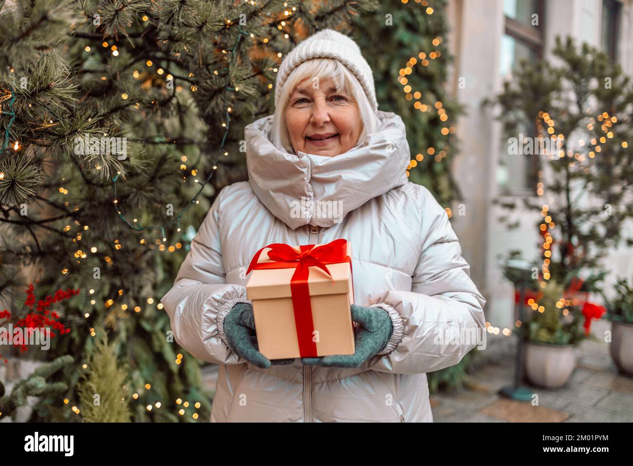 Joyeux Noël et joyeuses fêtes. Femme senior s'amusant avec boîte cadeau  surprise présent près de l'arbre de Noël en plein air au marché de Noël sur  la ville Photo Stock - Alamy