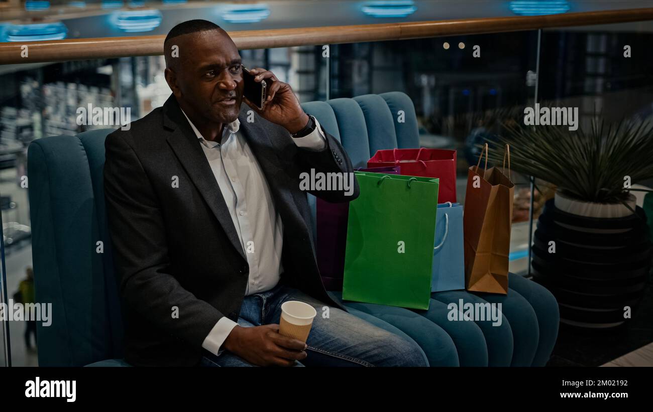 Homme d'affaires d'âge moyen adulte africain avec des sacs de shopping dans la boutique du centre commercial parler téléphone mobile parler des achats parler Banque D'Images
