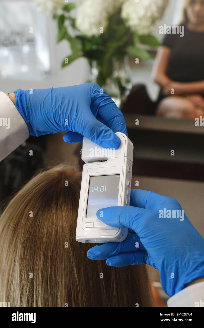 Vue rapprochée de la trichologue féminine examine la peau de la tête de la femme avec un système d'équipement spécial de dermatologie. Concept de perte de cheveux et de trichologie Banque D'Images