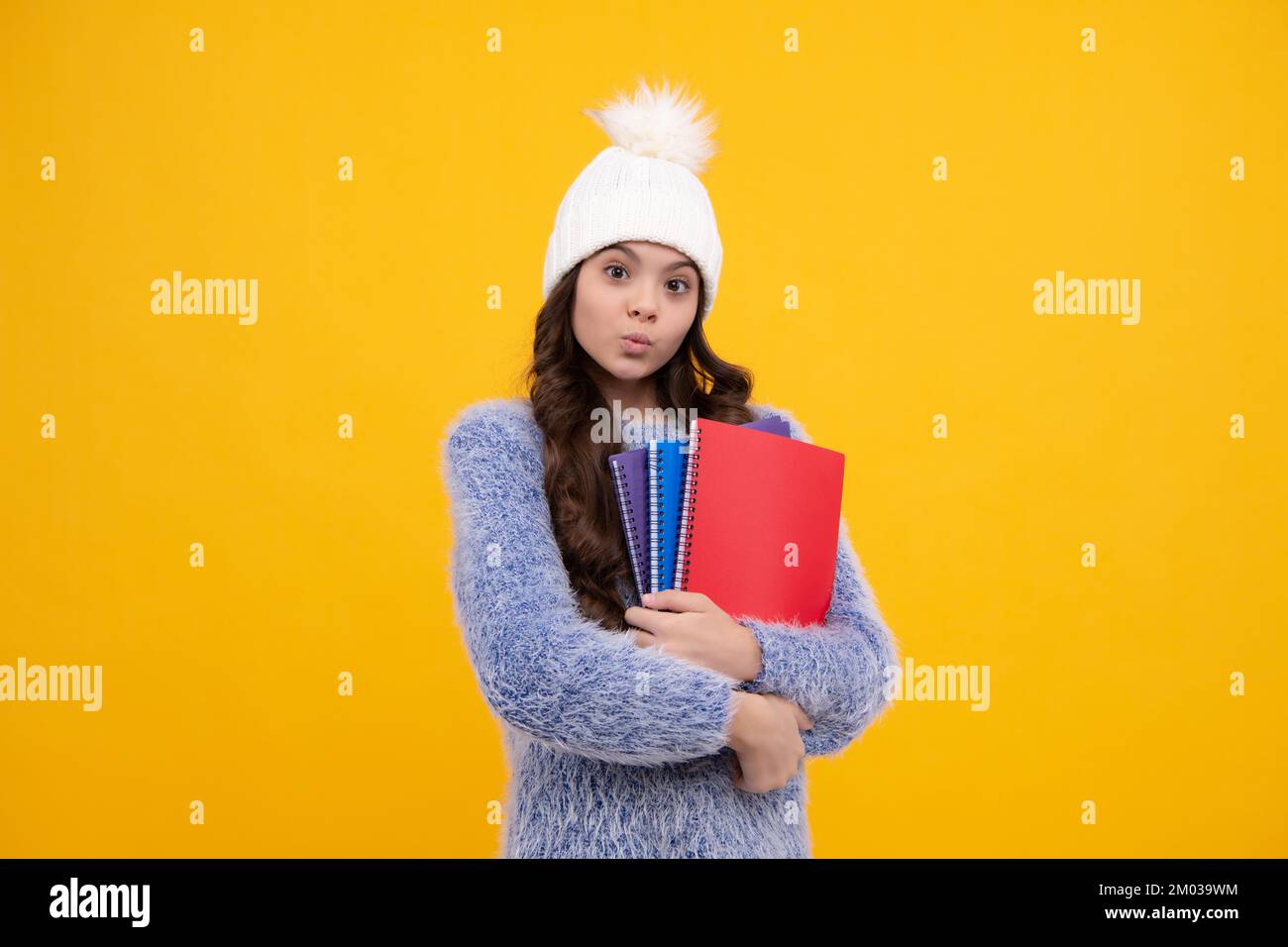 Portrait des filles adolescentes de l'école en automne chapeau tenant des copybooks et sac à dos sur fond jaune. École d'automne. Visage amusant Banque D'Images