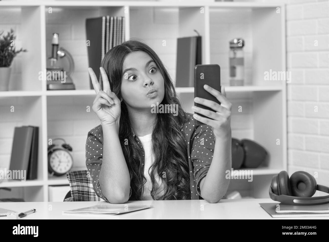 vlogger avec téléphone portable montre le geste de paix. bonne adolescente blogger utilisation de smartphone. retour à l'école. enfant faisant le selfie dans la salle de classe. septembre 1. enfant Banque D'Images