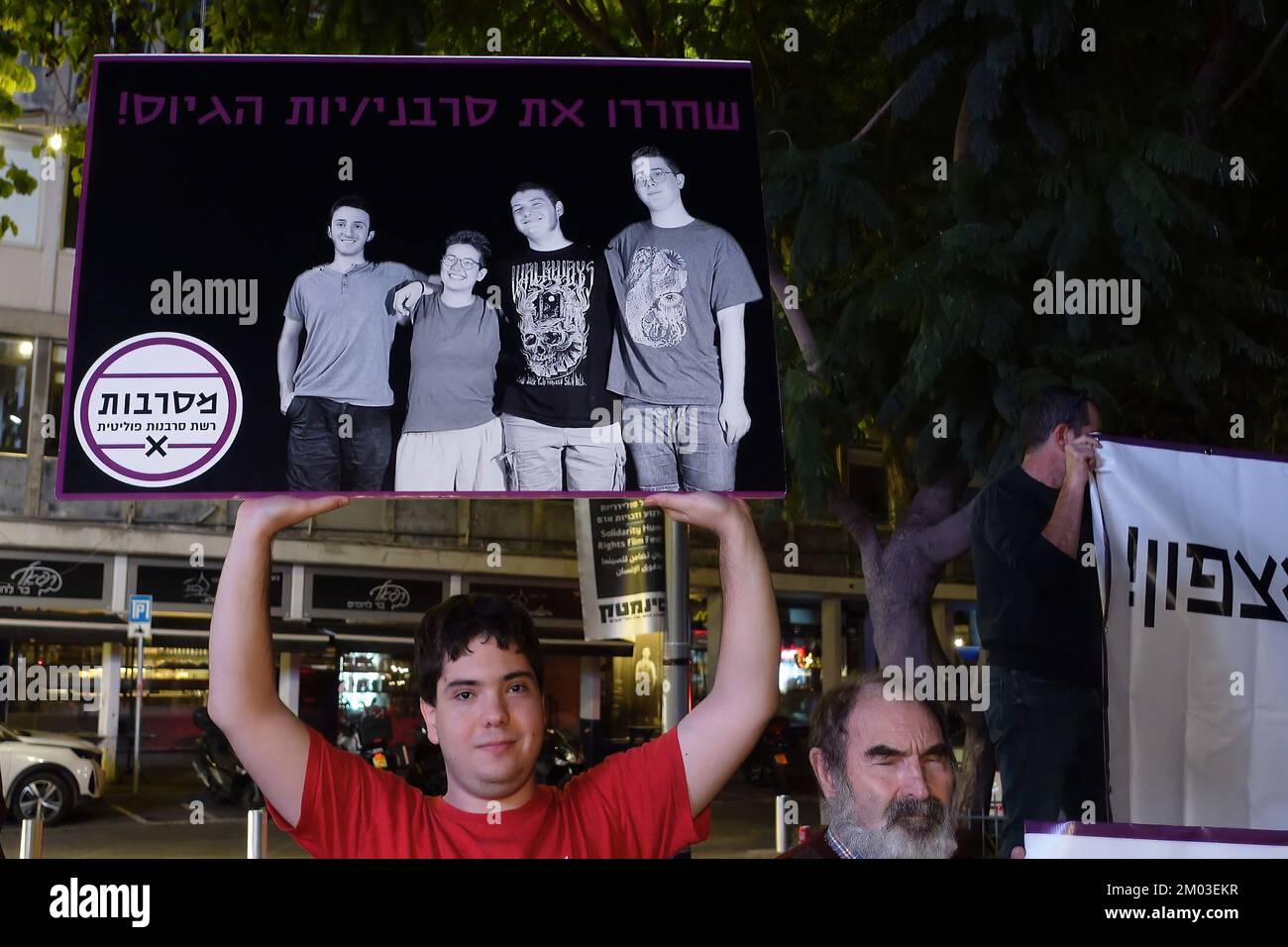 TEL AVIV, ISRAËL - DÉCEMBRE 3 : Un adolescent israélien porte un panneau qui montre la photo de jeunes objecteurs de conscience israéliens, actuellement emprisonnés dans une prison militaire parce qu'ils refusent de s'enrôler dans l'armée, lors d'un rassemblement appelant à leur libération sur 3 décembre 2022 à tel-Aviv, Israël. La conscription militaire est obligatoire pour les jeunes Israéliens, et le refus ou l’évasion de s’enrôler sans l’approbation de l’armée est une infraction punissable. Les objecteurs de conscience passent souvent des mois en prison militaire sur plusieurs périodes consécutives, jusqu'à ce que l'armée décide des libérer. Crédit : Eddie Gerald Banque D'Images