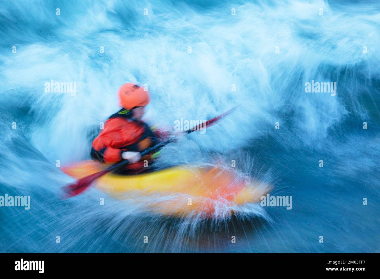 Kayak en eau blanche à travers une vague stationnaire sur la rivière Bow à Calgary, Alberta, Canada. Mouvement flou. Banque D'Images