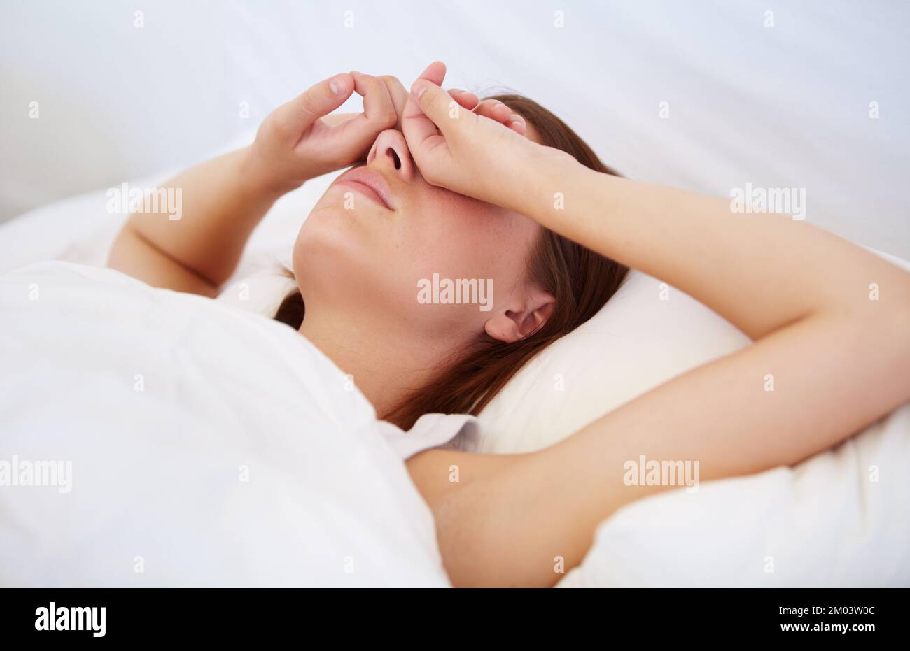 Pourquoi le matin est-il déjà. Une jeune femme couché au lit avec ses mains au-dessus de ses yeux. Banque D'Images